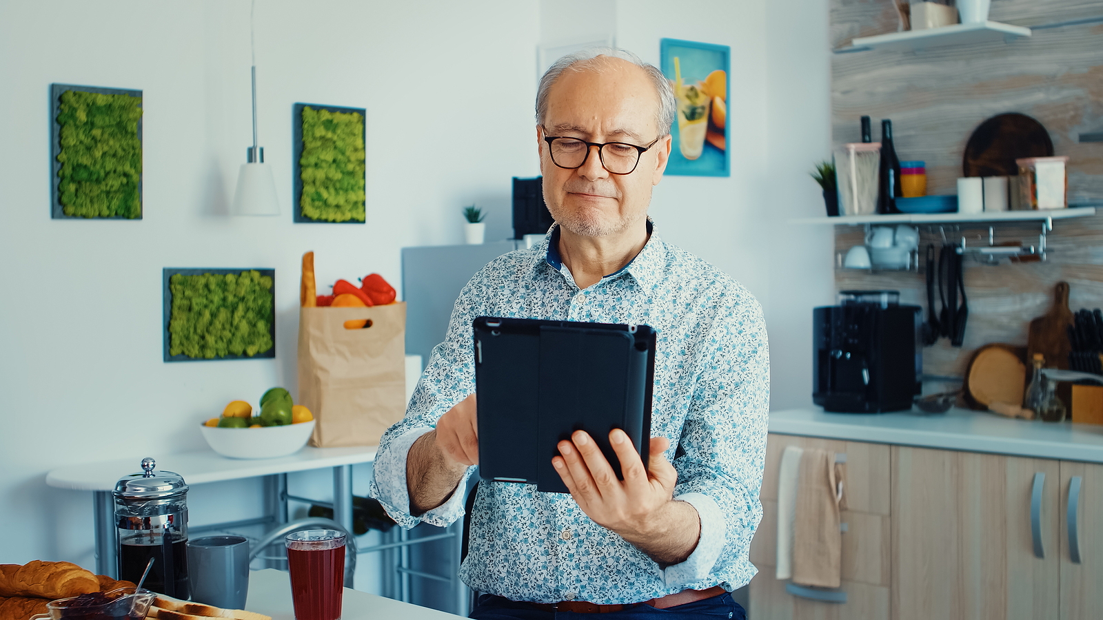 Photo of an older white man in a kitchen holding a