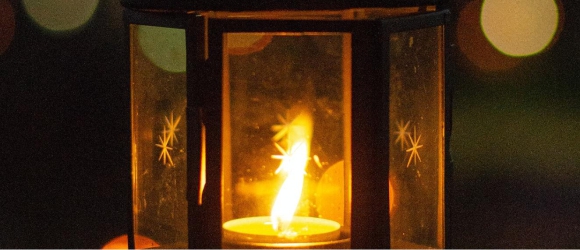 Photo of a metal lantern with a lit candle inside 